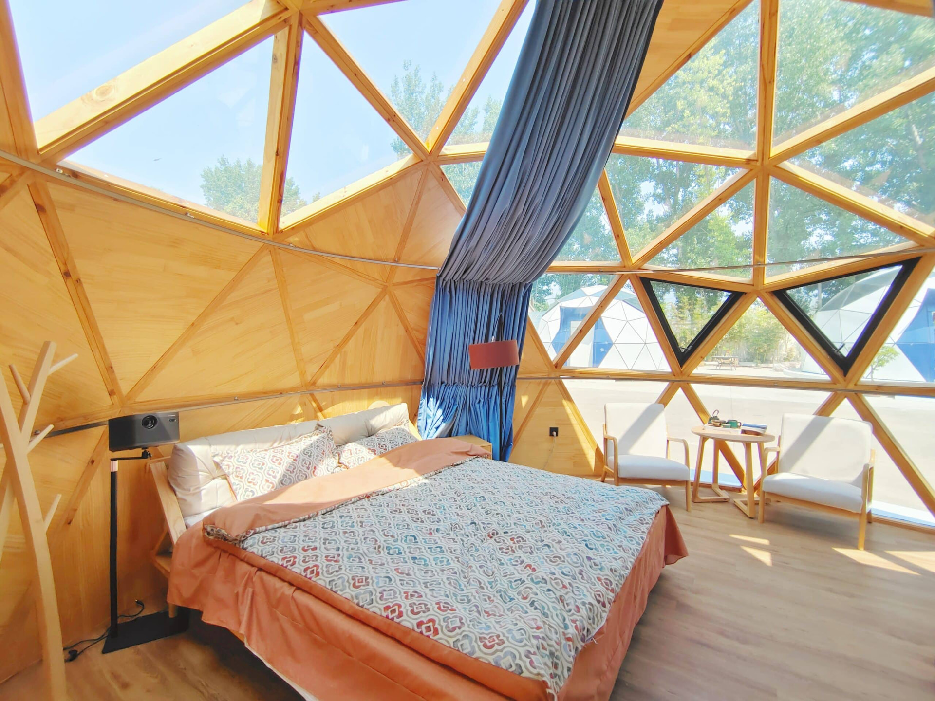 Real Solaris dome pod interior with king bed, wooden lining and triangular glazing